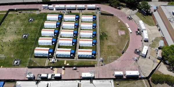 Aerial view of a field with multiple white tents and various vehicles around.