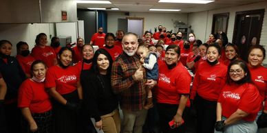 Group of people smiling and posing indoors, many in red shirts.