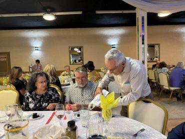 Man pouring wine for guests at a dinner event.