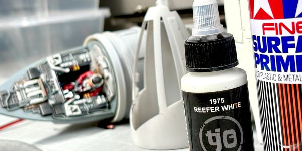 Close-up of model paint bottles with a detailed spaceship cockpit model in the background.