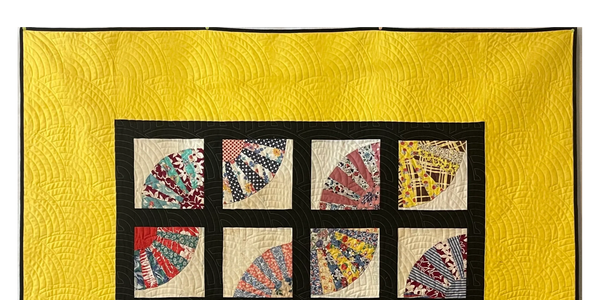 Colorful fan-pattern quilt with black grid and bright yellow border.
