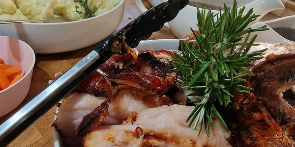 A plate of grilled meats garnished with fresh rosemary and tongs.
