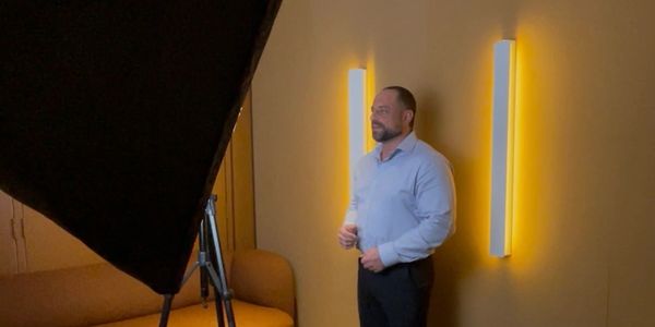 Man standing near a wall with glowing lights.