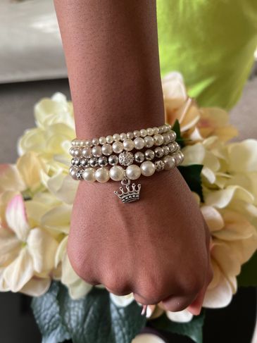 Wrist wearing faux pearl bracelets with a silver Princess charm
