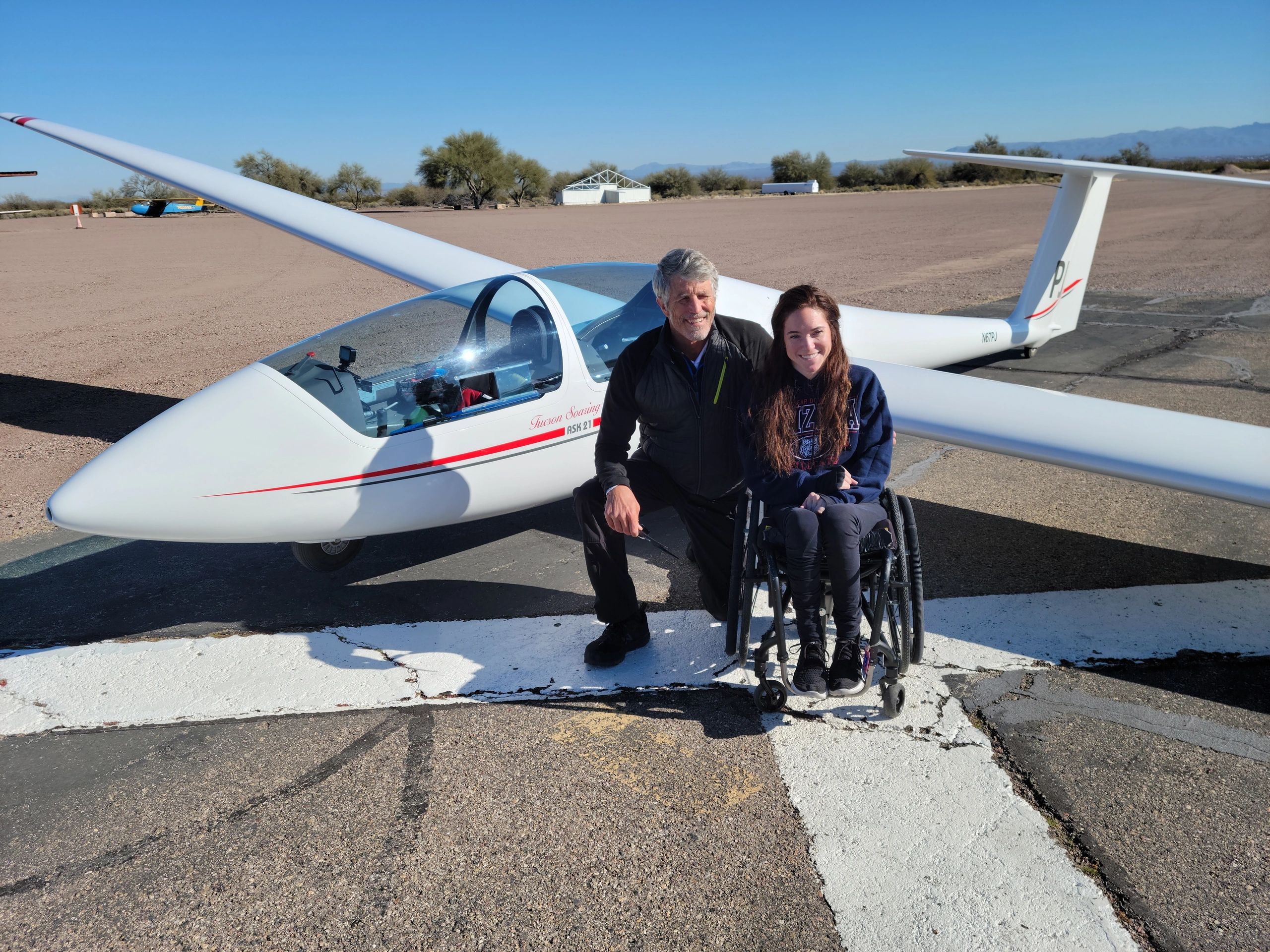 Instructor and wheelchair bound young woman next to the sailplane they just got out of.