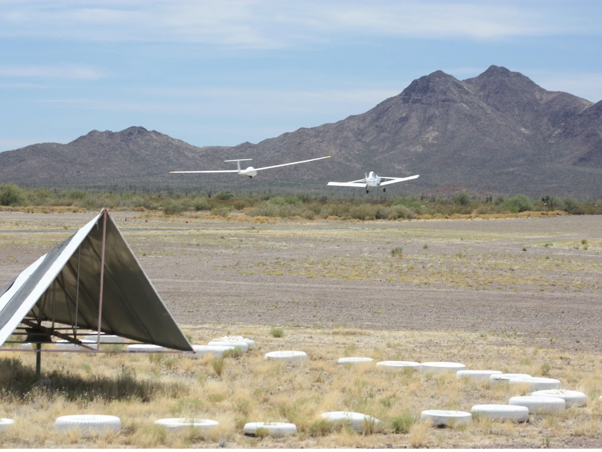 Glider being towed by the tow plane just after takeoff, with the beautiful mountains behind them.