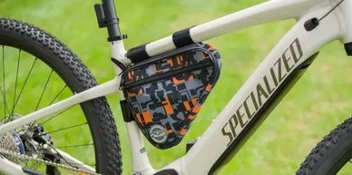 A white Specialized mountain bike with a camo-patterned frame bag.