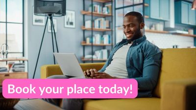 A man sat on a sofa smiling whilst looking at his laptop. He is sat in his modern apartment. 