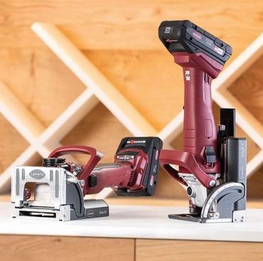 Two red cordless power tools on a wooden surface with a wine rack background.
