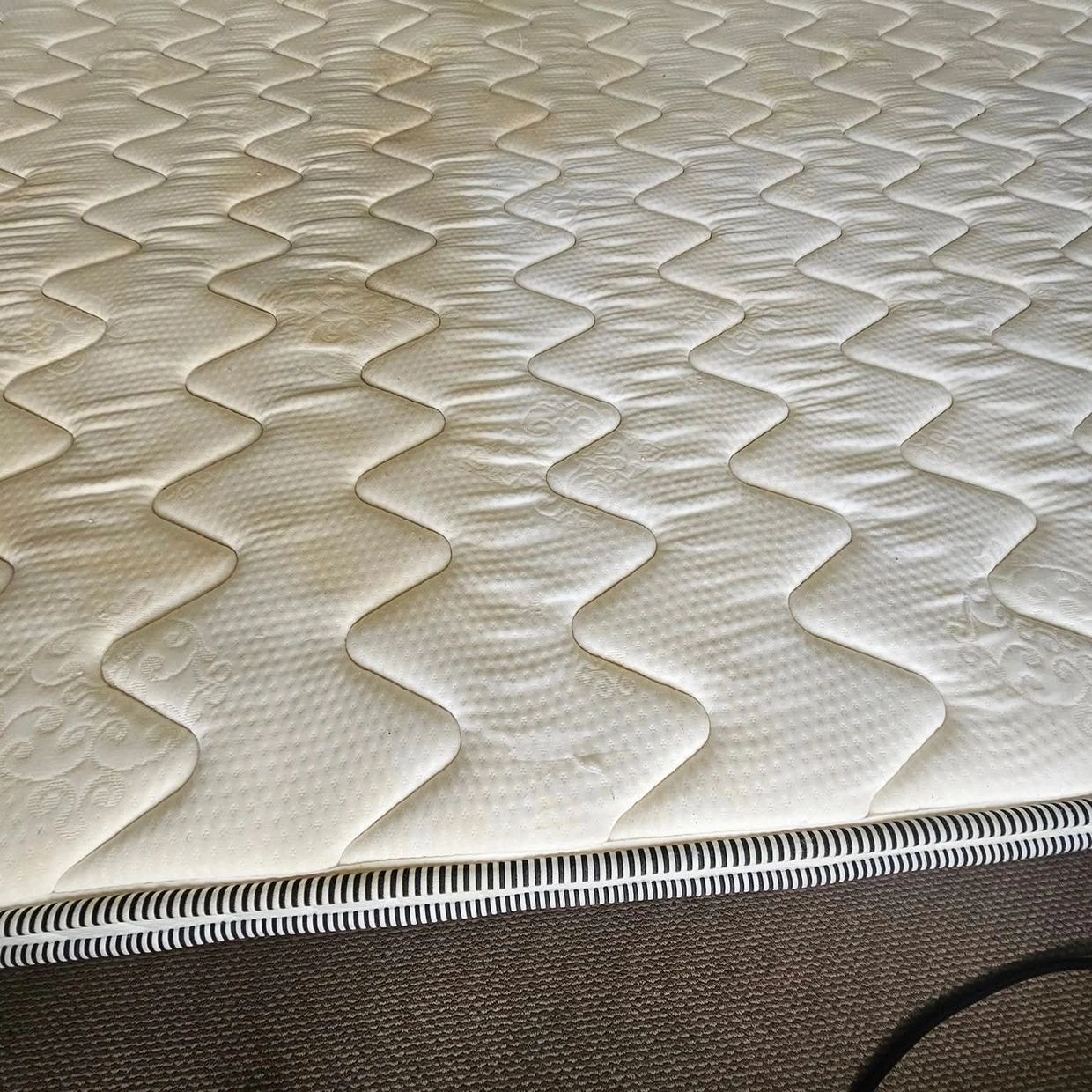 Close-up of a mattress with a wavy quilted pattern and striped edge.