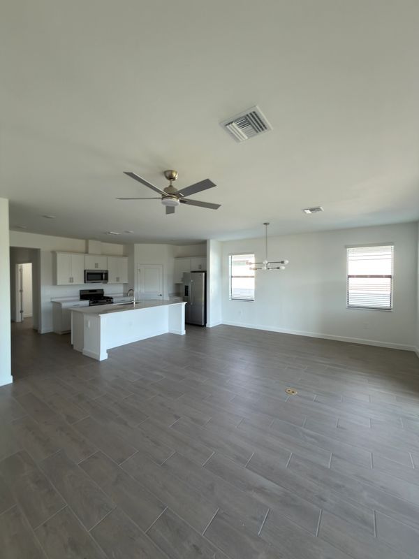 Spacious modern kitchen with white cabinets and gray tiled floor.