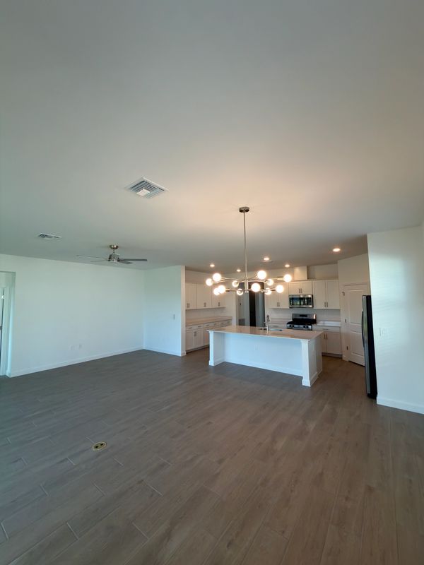 Spacious modern kitchen with white cabinetry and wood flooring.