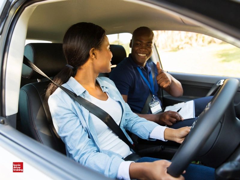 Driving instructor giving thumbs up to learner driver.