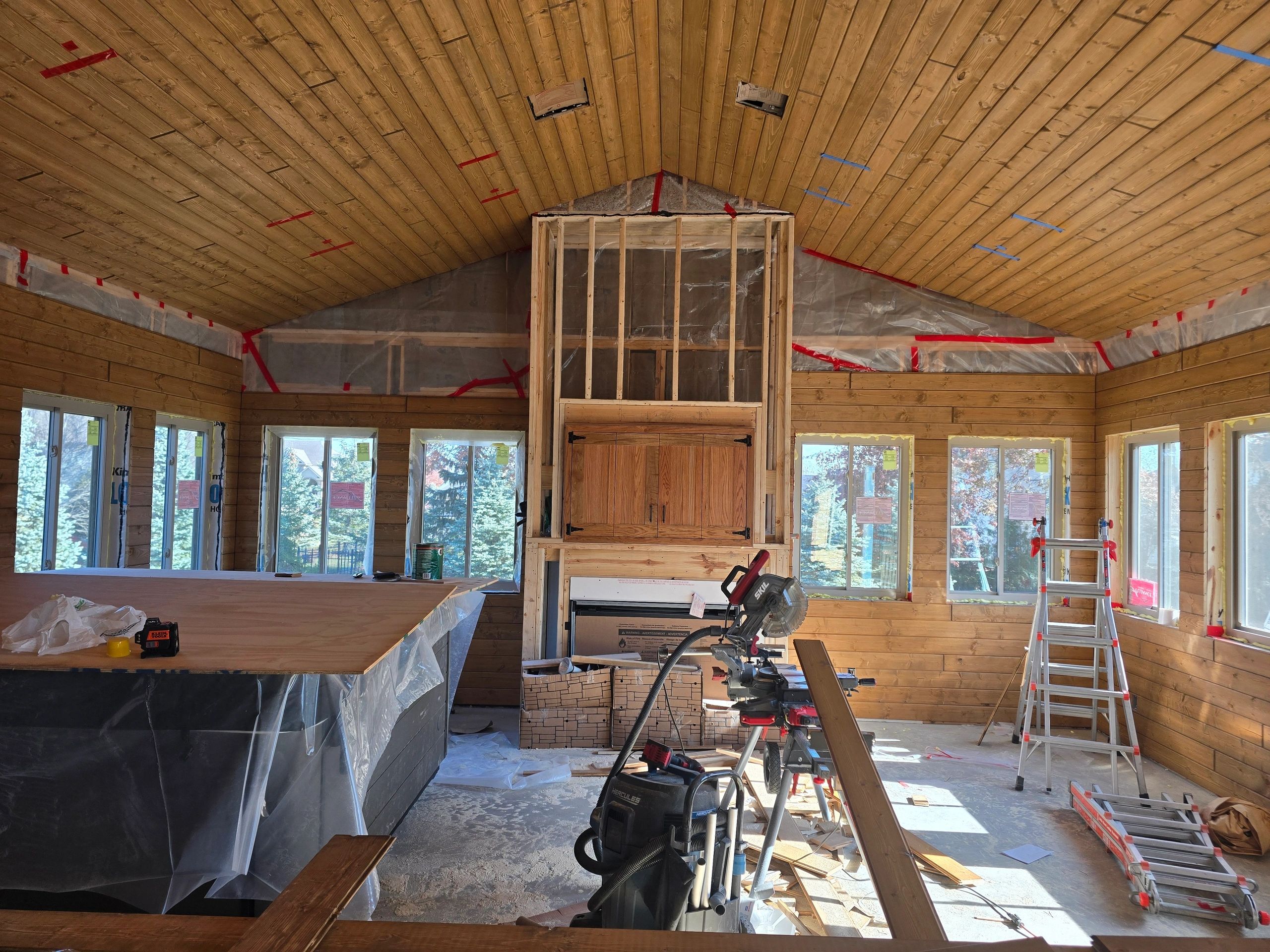 Interior of a wooden cabin under construction with tools and materials scattered.