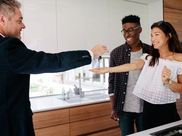 Estate agent handing over keys of new home to female buyer
