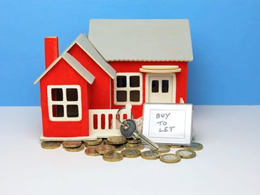 Buy To Let Key Ring And Key Outside A Scale Model Home.