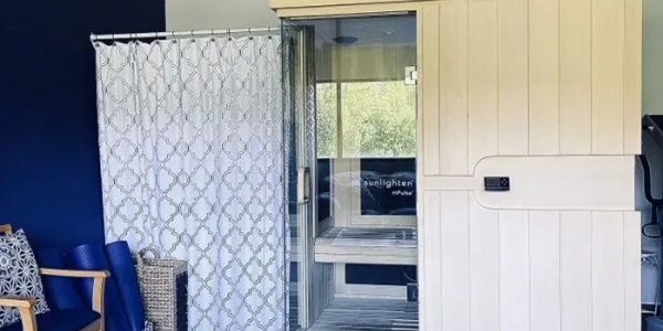 A modern sauna room with wooden panels and glass door.