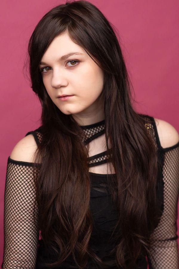 Young woman with long dark hair against a pink background.