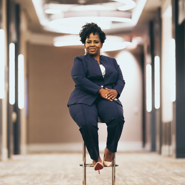 Black woman in a business suite sitting on a chair