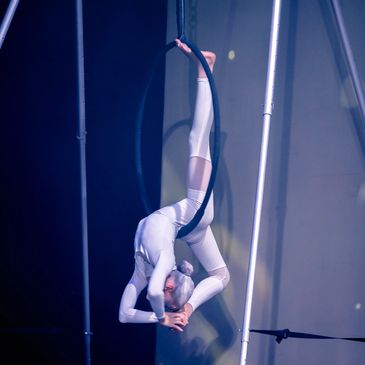 Aerialist performing on a hoop at night.