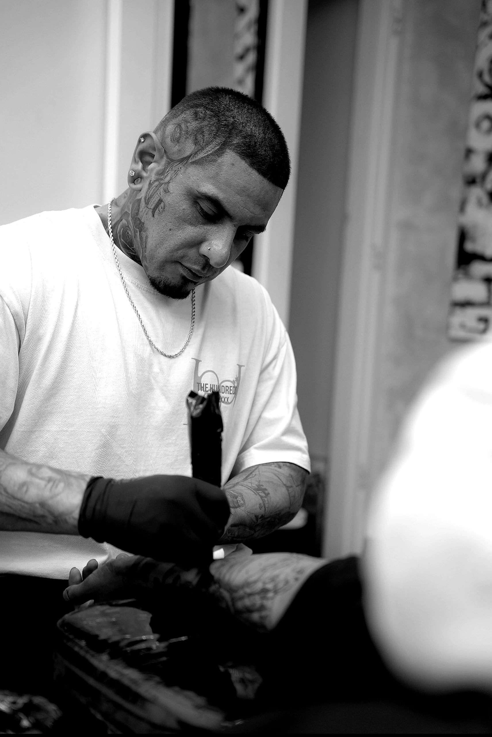 Tattoo artist deeply focused on his work in black and white.
