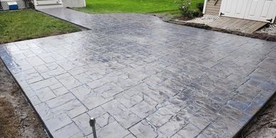 Stamped concrete patio with stone-pattern texture and sealed surface for durability.