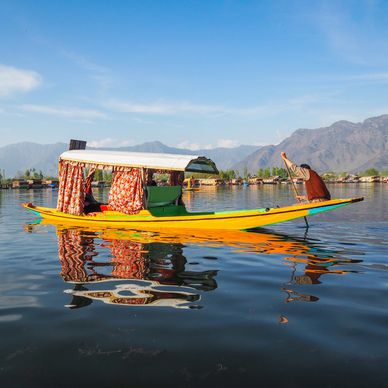A man paddling a colorful boat on calm water.