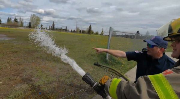 Firefighters practicing with a hose spraying water.