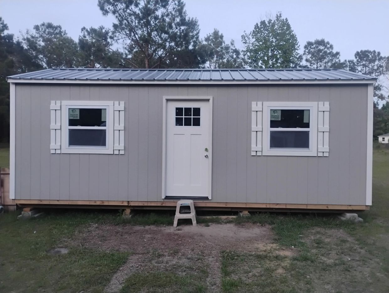 Small gray building with white door and windows.