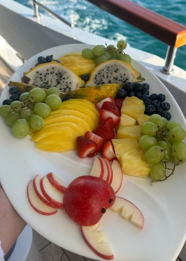 A vibrant fruit platter on a boat with a creative apple crab.