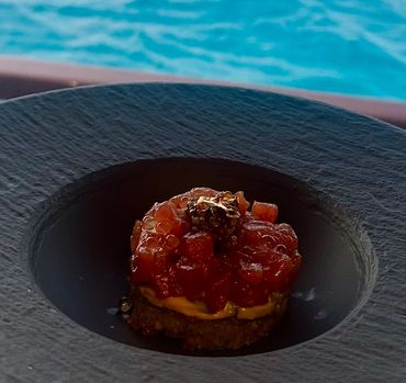 Gourmet tartare served in a black bowl with a poolside backdrop.
