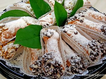 Pastry sticks topped with powdered sugar and chocolate chips, garnished with green leaves.