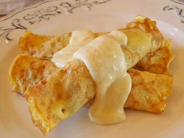 Two crepes topped with creamy sauce on a decorative plate.