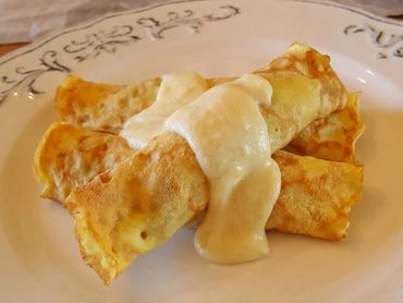 Two crepes topped with creamy sauce on a decorative plate.