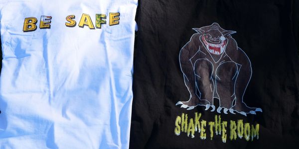 Two graphic t-shirts: one says 'BE SAFE,' the other shows a monstrous creature with 'SHAKE THE ROOM.'