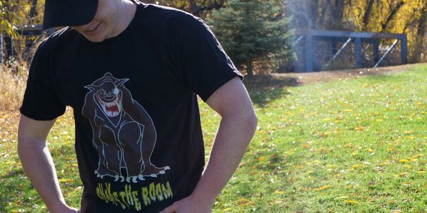 Man wearing a black T-shirt with a growling wolf graphic outdoors.