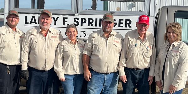Group of six workers in uniform standing outdoors.