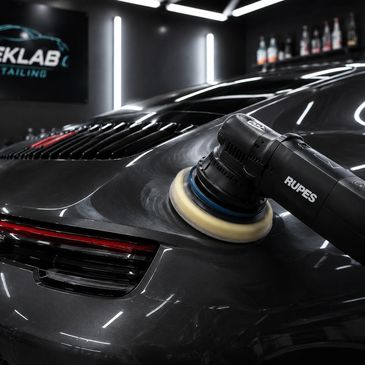 A car being polished with a Rupes buffer in a detailing shop.