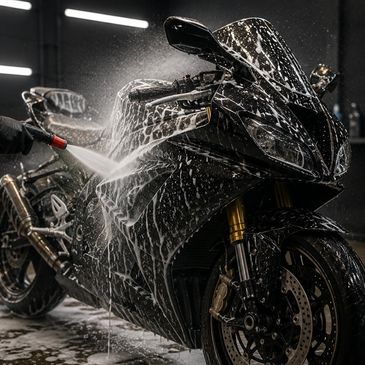 A black sport motorcycle being washed with soap and water indoors.