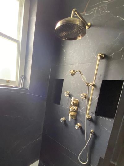 Wall-mounted shower installation featuring an overhead rainfall shower, handheld shower and exposed 
