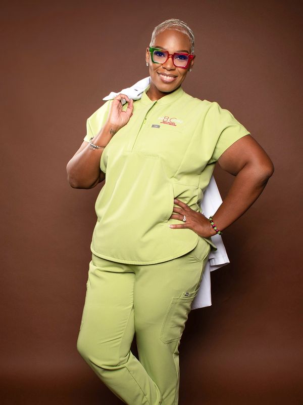 Confident woman in light green scrubs with colorful glasses.