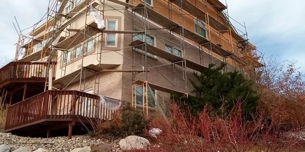 A house under construction with scaffolding around it and a wooden deck.