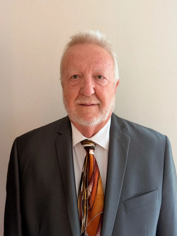 Elderly man in a formal suit with a colorful patterned tie.