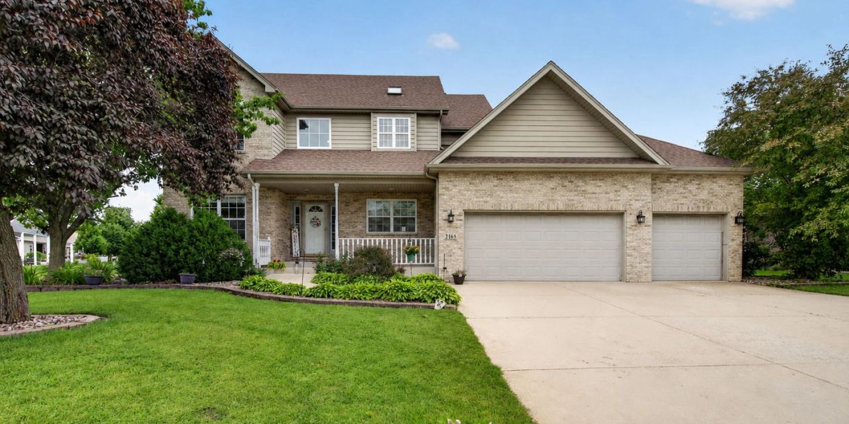 Spacious two-story suburban house with a three-car garage and well-kept lawn.