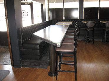 Empty dining area with black leather seating and stools.