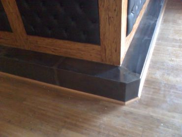 Black tiled baseboard with wooden wall panel and wooden floor.