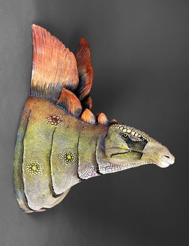 Colorful, detailed dinosaur head sculpture with textured scales and fins.
