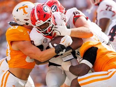 Two Tennessee players tackle a Georgia football player during a game.
