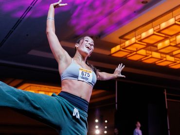 A woman joyfully dancing at an indoor event with vibrant lighting.