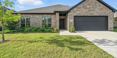 Brick house with a two-car garage and a front lawn.